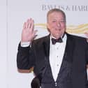 Sir Stephen Fry holding his hands up and smiling