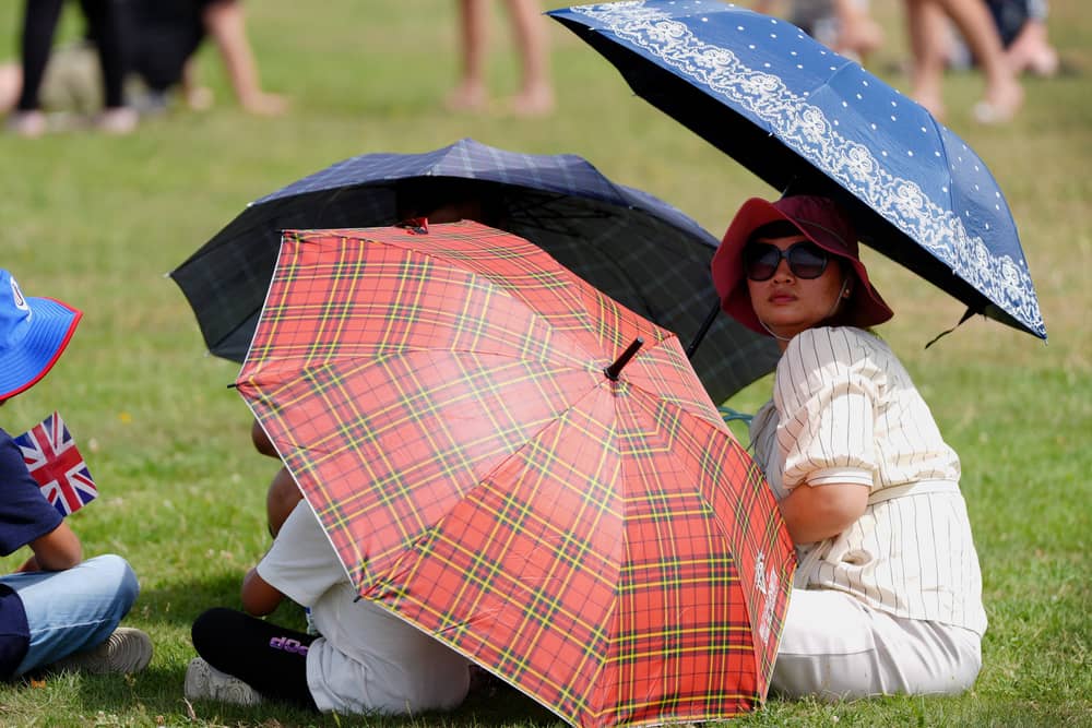 A family shelter under umbrellas during an Armed Forces Day event in Aldershot, Hampshire, on Saturday