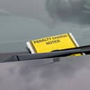 A penalty charge notice parking fine attached to car windscreen