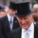 The King smiles, wearing a top hat