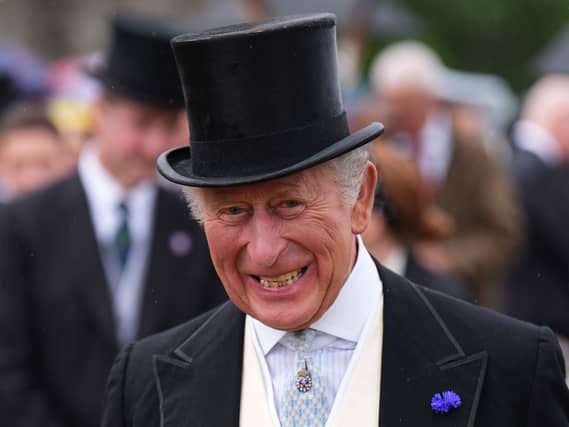 The King smiles, wearing a top hat