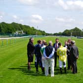 Jockeys, trainers, members of the BHA and ground staff inspect where a big hole has developed in the racing surface at Haydock