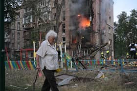 A woman walks past a burning building after a Russian missile attack in Kyiv
