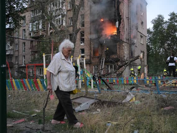 A woman walks past a burning building after a Russian missile attack in Kyiv