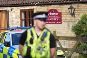 An out-of-focus police officer in front of Johnsons of Old Hurst zoo