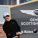 Rory McIlroy tees off in front of a Genesis Scottish Open sign