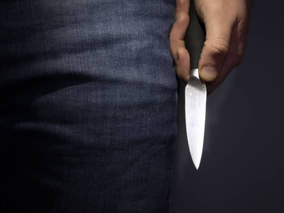 A model poses holding a knife.