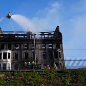 Firefighters spray water from a high platform on to a building which shows signs of extensive fire damage