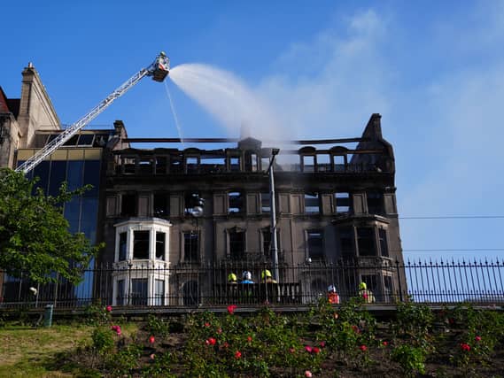 Firefighters spray water from a high platform on to a building which shows signs of extensive fire damage