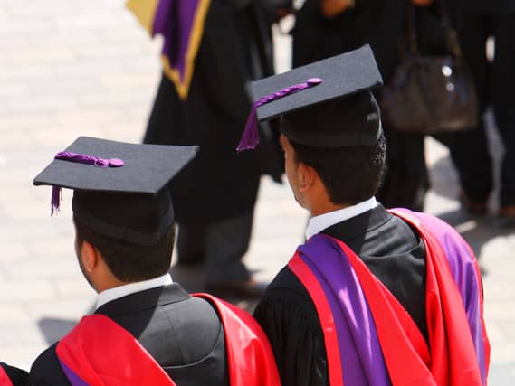 The backs of students in graduation hats and gowns