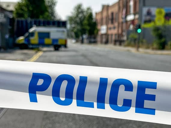 Police tape in the foreground and a police van in the background on a residential street