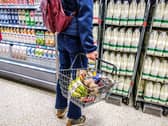 A woman holds a shopping basket in the aisle of a supermarket