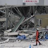 A rescue worker walks in front of Aeon Mall, which was damaged by an explosion following an earthquake