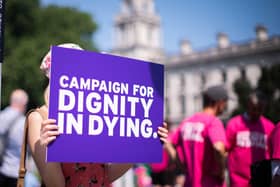 A person holding a sign saying campaign for dignity in dying