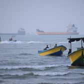 Small boats line the shore as cargo ships and other commercial vessels appear anchored in the Strait of Hormuz