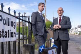 SNP MP Dave Doogan and First Minister John Swinney stand at a polling station's railings