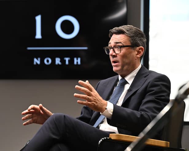 Andy Burnham talks in front of a TV screen with a logo for Number 10 North