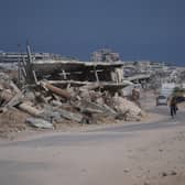 A Palestinian man rides his bike by the rubble of buildings that were destroyed during the Israel-Hamas wa