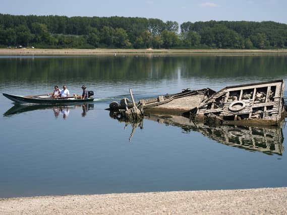 People watch the wreckage of a Second World War German warship, emerged due to the drought, in front of Djerdap II, a large dam on the Danube River, between Romania and Serbia, near Prahovo, Serbia