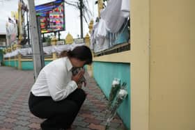 A woman lays flowers and offers prayers at Debsirin Nonthaburi School