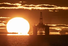 The sun rising behind a redundant oil platform moored at sea