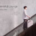 Passenger going up an escalaot in front of Revolut Lounge branding