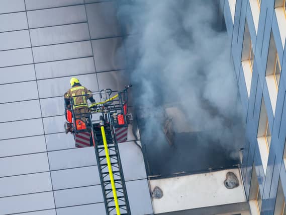 Firefighters in a cherrypicker as smoke pours out of a building
