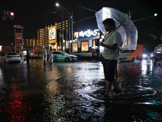 Torrential rain floods a road, causing a car to stall, in Ichikawa, Chiba prefecture, Japan,