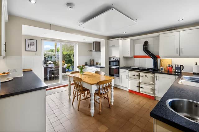 The spacious kitchen includes a breakfast table, ample storage and doors opening onto a private south-facing patio