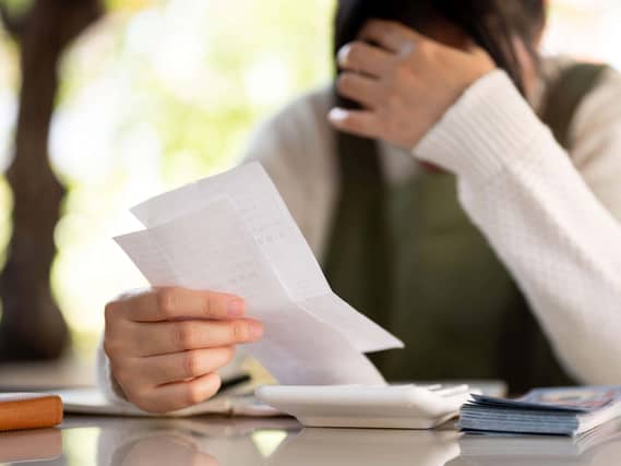 A woman with their hand on their head in distress while reading paperwork