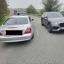 Innocent Ayodele (half cut off at the right) next to his car which is facing the opposite direction to the other cars