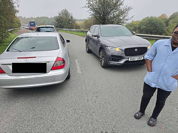 Innocent Ayodele (half cut off at the right) next to his car which is facing the opposite direction to the other cars