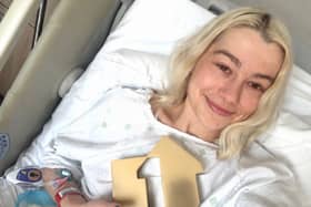 Phoebe Bridgers smiling while lying in a hospital bed