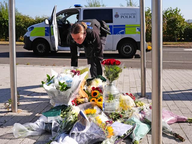 A police officer leaves flowers at the Cleveland Police HQ Memorial Garden in Middlesbrough, following the line-of-duty deaths of PC Matthew Blades and PC Tom Clough