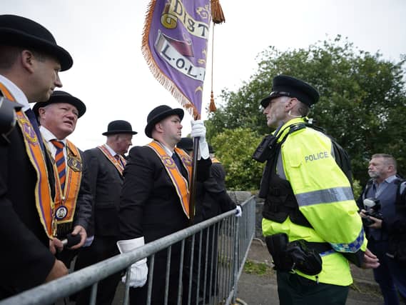 A police officer speaks to members of the Orange Order