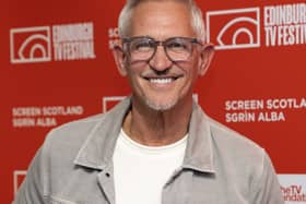 Gary Lineker wearing a white T-shirt and grey jacket smiling in front of a red banner promoting the Edinburgh TV Festival