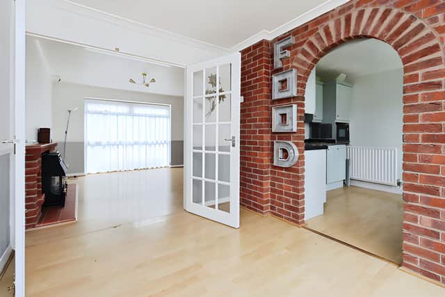 The bright living room looks over the front garden and includes a feature fireplace and staircase to the first floor