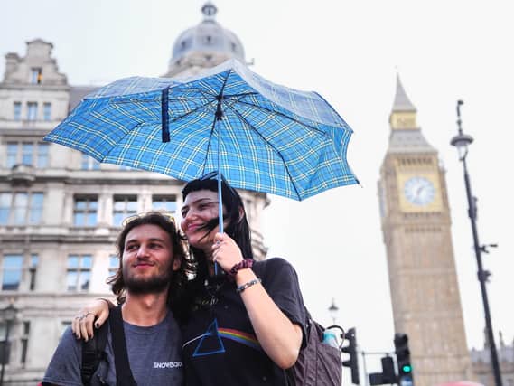 People shelter from the rain under an umbrella, in Westminster, central London.