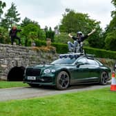 A man wearing a helmet sitting on top of a car.