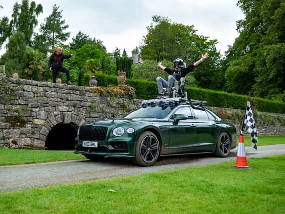 A man wearing a helmet sitting on top of a car.
