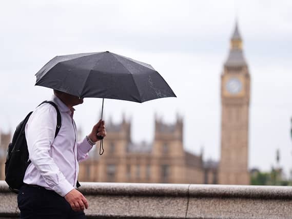 A person uses an umbrella while out walking, with the Houses of Parliament in the background