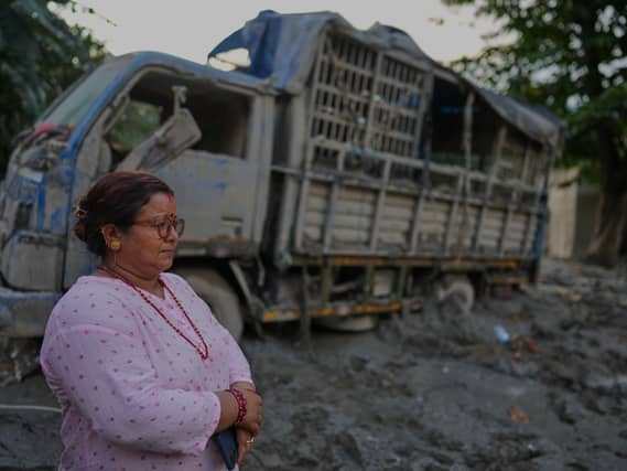 A woman standing next to a wrecked truck in Nepal