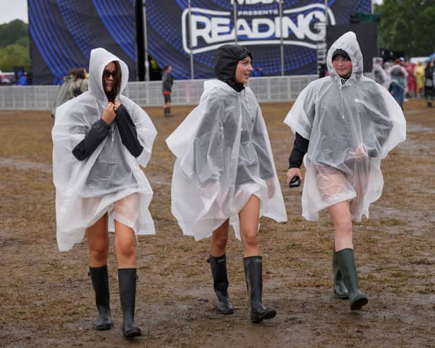 Festivalgoers cover up with plastic ponchos for the heavy rainfall at the Reading Festival at Little John’s Farm, Reading, Berkshire.