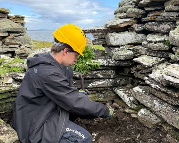 A person in a hard hat working within a ruin