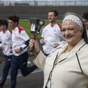 Frances Connolly ringing a bell as she stands trackside in front of people running