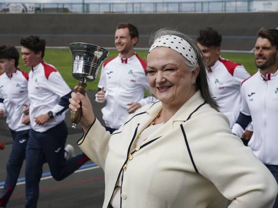 Frances Connolly ringing a bell as she stands trackside in front of people running
