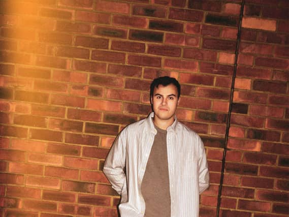 Freddie Meredith leaning against a brick wall with his hands in his pockets