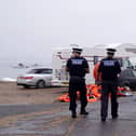 Police officers walk past a pile of discarded life jackets at Eastney Point, near Eastney Beach, Portsmouth