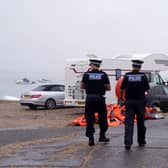 Police officers pass a pile of discarded life jackets