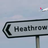 A view of a road sign for Heathrow, with a plane taking off in the background